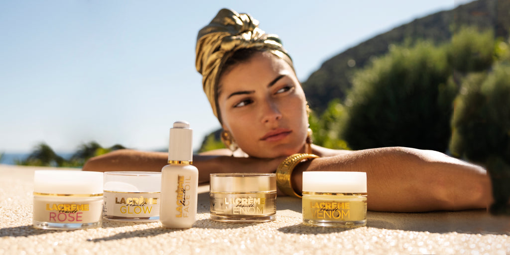 woman in a gold turban leaning over the edge of a swimming pool, with a range of lacreme beaute products in front of her